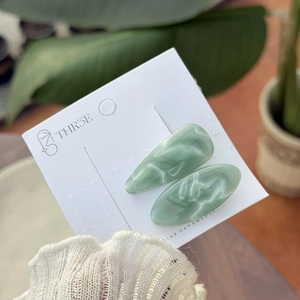 Détail de barrettes en acétate vert menthe marbré sur une carte de présentation blanche