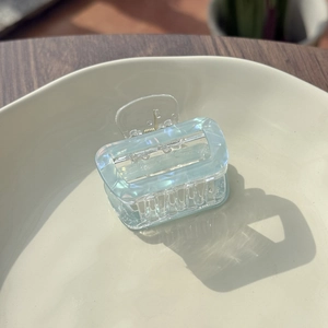 Close-up of translucent light blue square hair claw clip with pearlescent marble texture