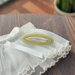 Olive green oval hair clip with sparkling rhinestones on an elegant lace background