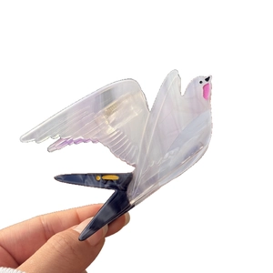 Translucent bird hair claw clip in acetate with elegant pearlescent gradient wings