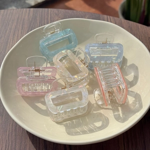Close-up of colorful hollow rectangular hair claws in a bowl on a wooden table