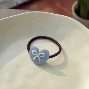 Brown elastic hair tie featuring a blue resin heart charm with a white bow decoration