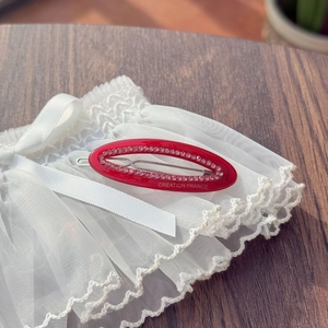 Detail of red oval hair clip with pink rhinestones and gold Creation France lettering
