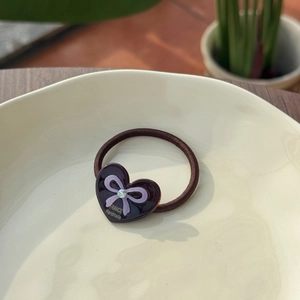 Detailed macro view of heart-shaped resin charm with bow and diamond on elastic hair band