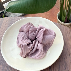 Chouchou plissé élégant en satin vieux rose présenté sur une assiette blanche décorative