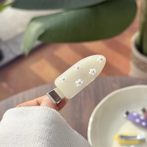 Crèmewitte matte haarklem met 3D-madeliefjes en goudkleurige accenten op de clip