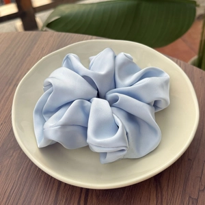 Chouchou élégant en satin bleu ciel avec texture soie et plis souples sur plateau