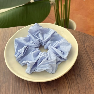 Elegant soft fabric scrunchies in pastel blue and purple on a ceramic display plate