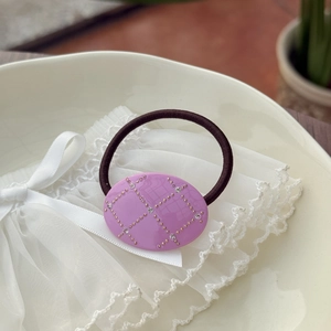 Pink oval acetate hair tie with grid pattern and small rhinestones on an elastic band