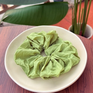 Close-up of grass green scrunchie with soft fabric texture on a white plate