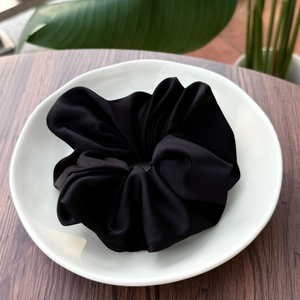 Gros plan d'un chouchou en satin noir élégant posé sur une assiette en céramique