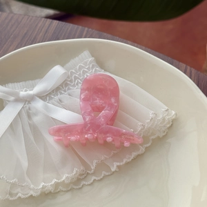 Pink marble acetate hair claw clip with gold lettering on a white lace background