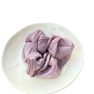 Chouchou plissé lilas à effet soyeux sur une assiette minimaliste en céramique