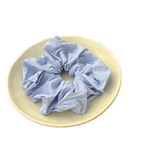 Light blue fabric scrunchie with soft pleated texture on a white decorative plate