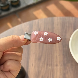 Detail van een roze hars haarklem met kleine witte bloemen op een houten achtergrond