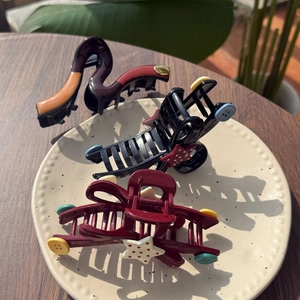 Three assorted claw clips featuring stars and buttons displayed in a ceramic tray