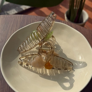 Dettaglio di fermagli per capelli in resina ambrata con decori a cuore e fiori