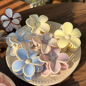 Detail view of colorful jelly-textured flower hair claws in a ceramic dish on wooden table