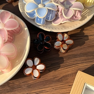 Detailed close-up of jelly color flower hair claws in multiple pastel shades on a wooden table