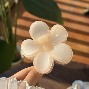 Detail of a creamy jelly flower hair claw clip held in hand with soft natural sunlight