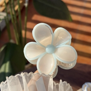 Detailed macro view of jelly blue and cream white translucent floral hair claw clip