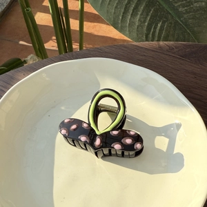 Gros plan d'une pince à cheveux contrastée à pois roses dans un plat en céramique