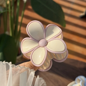 Close-up of a pink and cream jelly-colored floral hair claw clip held in hand