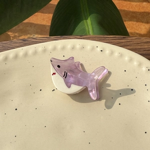 Pince à cheveux requin en acétate violet avec fini nacré sur une assiette en céramique