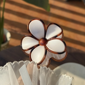 Detail of cream translucent flower hair claw with tortoiseshell edges and center bead