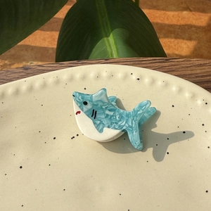 Détail d'une pince à cheveux requin en acétate bleu et blanc avec texture marbrée