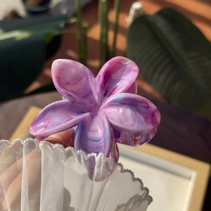 Dettaglio macro della molletta a fiori viola marmorizzati con finitura lucida e chic