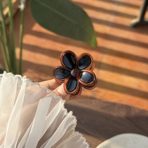 Detailed close-up of amber translucent resin flower hair claw with a glossy black center