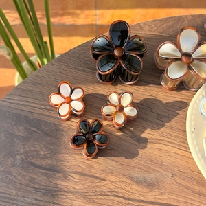 Detailed view of jelly-colored flower hair claws with brown gradient edges on wood