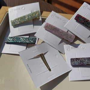 Detail of floral engraved acetate hair clips in assorted colors on display card