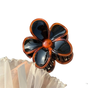 Floral jelly-colored hair claw clip with black petals and tortoiseshell edge finish