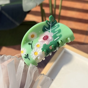 Détail de la pince à cheveux en acétate vert menthe avec motifs marguerites et feuilles