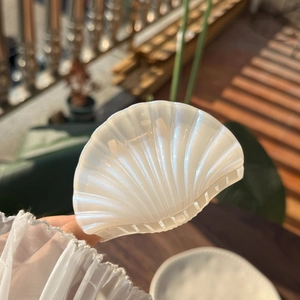 Elegant pearl white shell hair claw clip with iridescent finish held in a garden