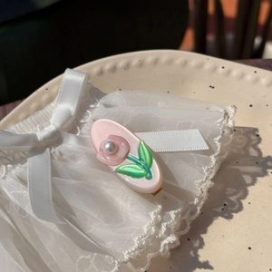 Pince à cheveux tulipe en acétate rose avec perle sur fond de dentelle élégante