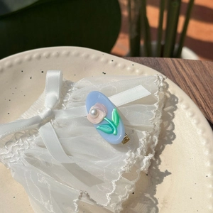 Détail de la pince à cheveux tulipe en acétate bleu avec fleurs roses et perle