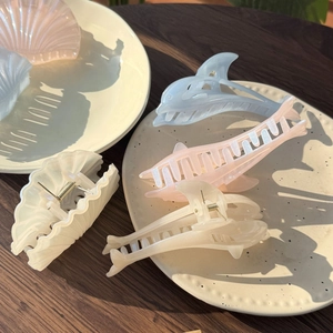 Detail of seashell and dolphin hair claws with a shimmering finish in sea colors