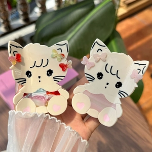 Close-up of cat-shaped acetate hair claw clips with bow details and heart paw prints