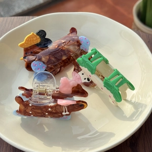Three acetate hair claws featuring dachshund and green fence patterns on ceramic plate