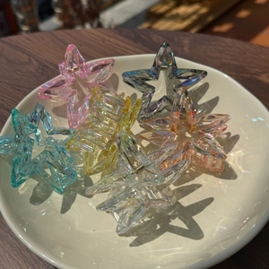 Detailed view of six colorful star-shaped hair claws with transparent iridescent finish