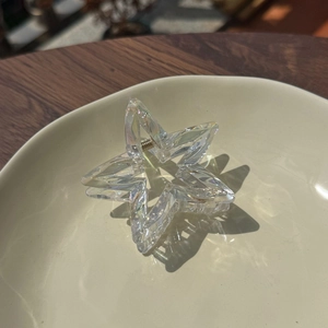 Iridescent star-shaped hair claw clip with transparent finish on a textured background
