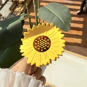 Pince à cheveux tournesol tenue à la main avec pétales jaunes et centre texturé