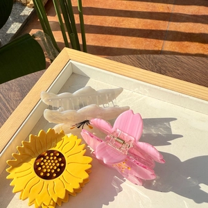 Vue détaillée de trois pinces à cheveux en acétate aux motifs de tournesol et lys