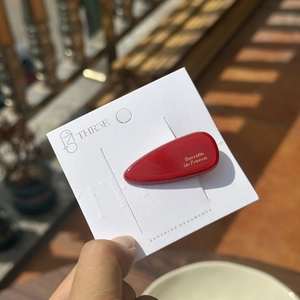 Détail macro d'une barrette à cheveux rouge en acétate avec texte doré Barrette La France