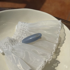 French style grey-blue acetate hair clip with gold label on white lace fabric