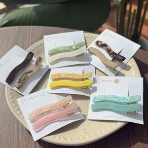 Detailed close-up of colorful wave acetate hair clips set in a ceramic tray