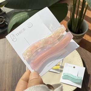 Close-up of pink wave cellulose acetate hair clips with golden brand label detail